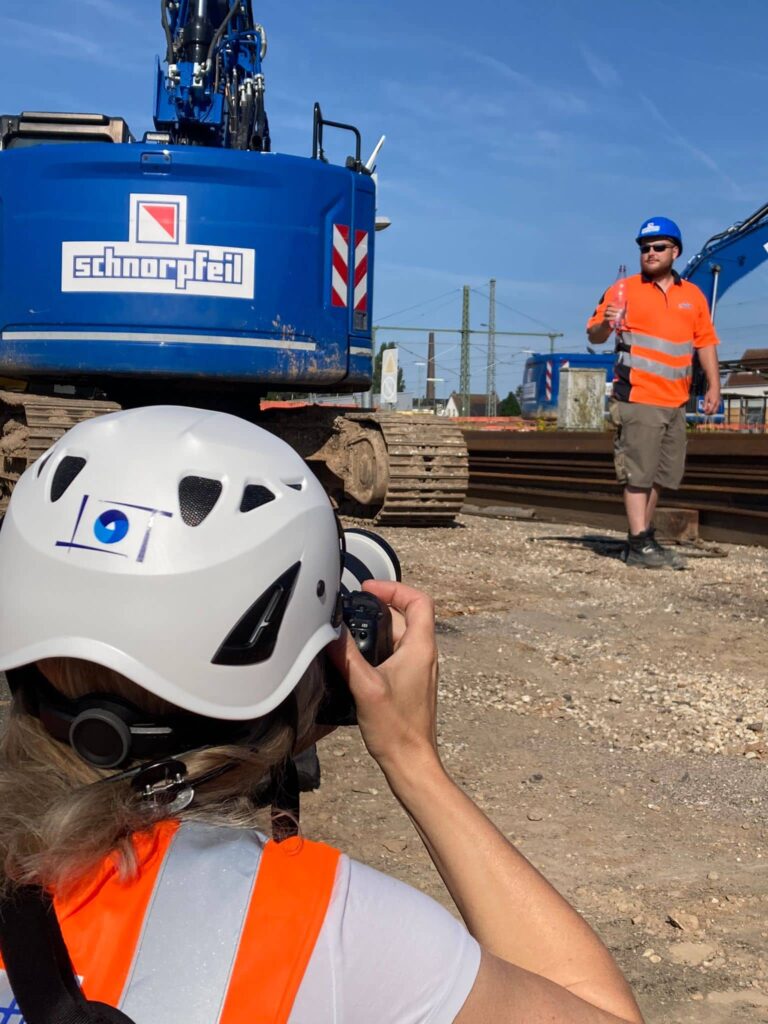 Britta Hilpert Baufotografin auf einer Baustelle mit Bagger im Hintergrund.