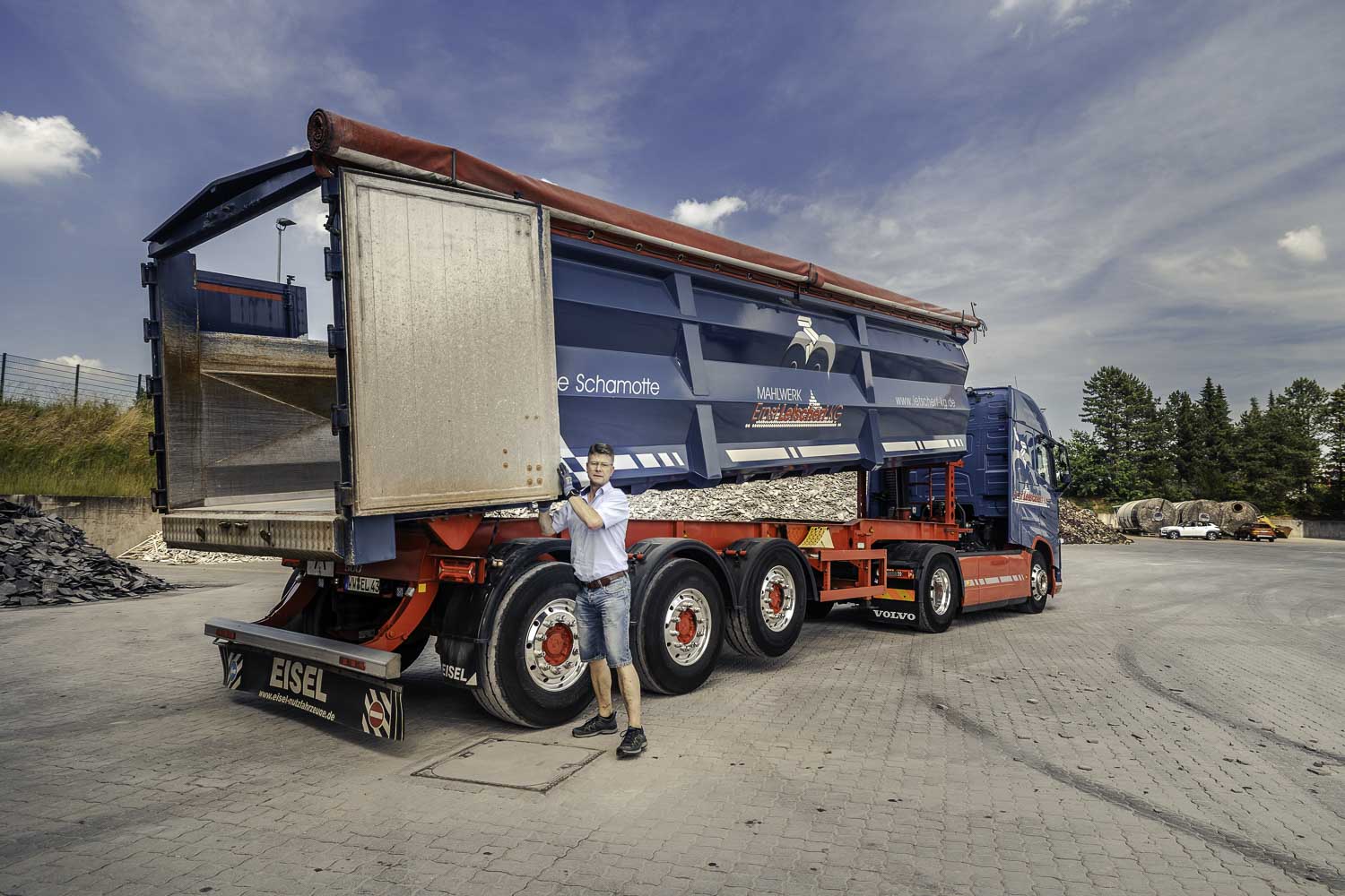 Industriefotografie: Der LKW-Fahrer schließt die Mulde des Muldenkipper-LKW